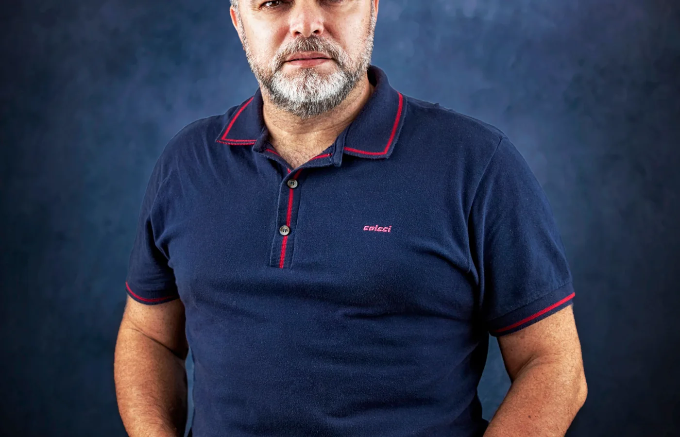 Homem adulto usando polo azul-marinho em composição casual